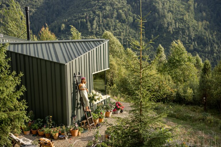 Woman on Ladder by Eco-Friendly House in Green Mountain Garden